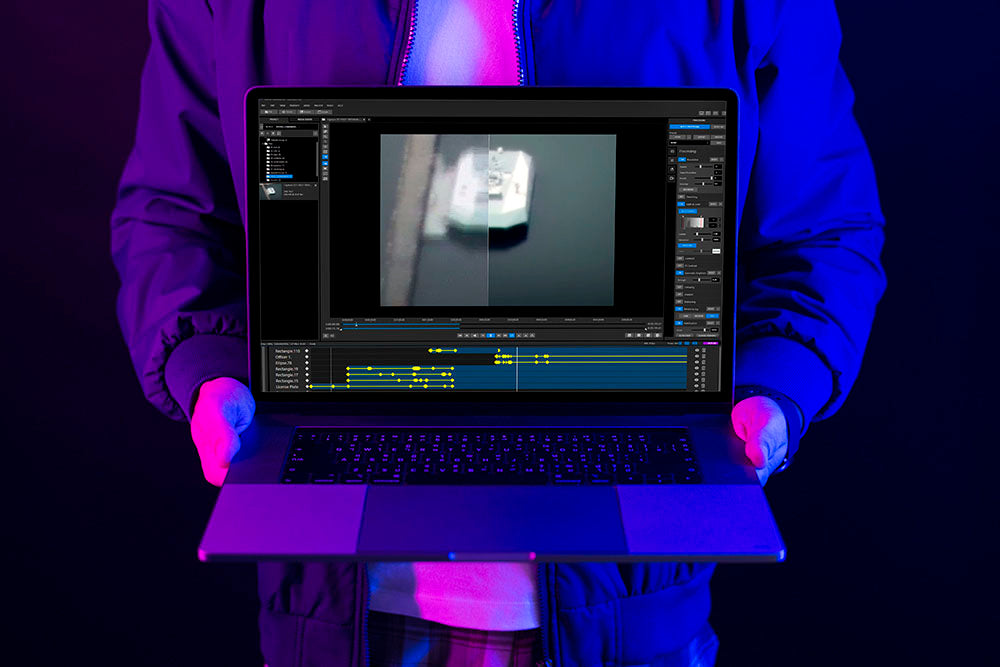 Man holding laptop running Forensic enhancement software.