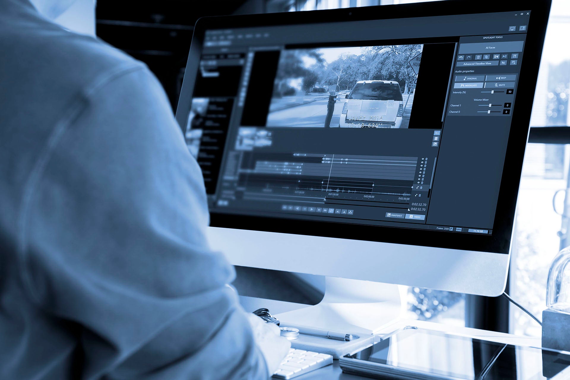 Man working at desktop computer with Spotlight redaction software.